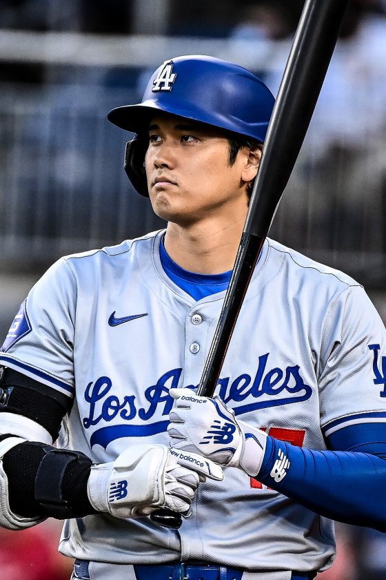 Shohei Ohtani holding a bat on his shoulder in a Los Angeles Dodgers helmet and gray road uniform at Nationals Park, April 2024